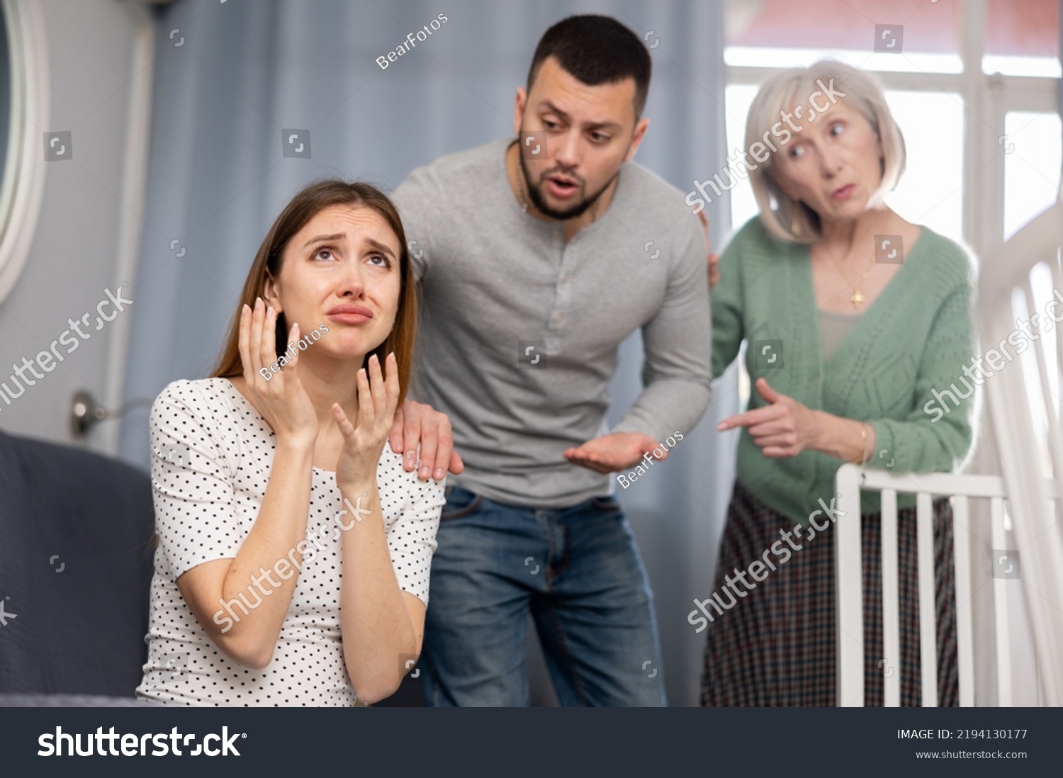 Offended woman sitting on sofa in apartment. Her husband and mother-in-law quarreling with her. #2194130177