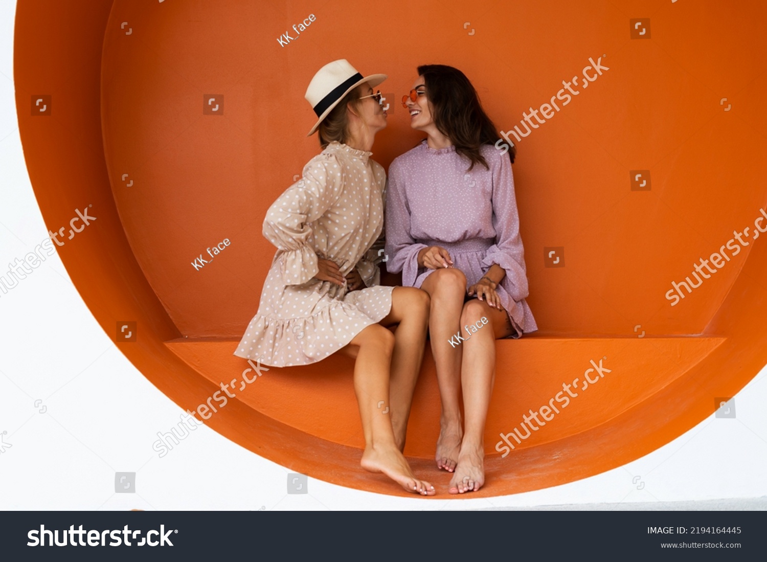 Two young beautiful smiling hipster female in trendy summer sundress.Sexy carefree women posing on the street orange background. Positive models having fun #2194164445