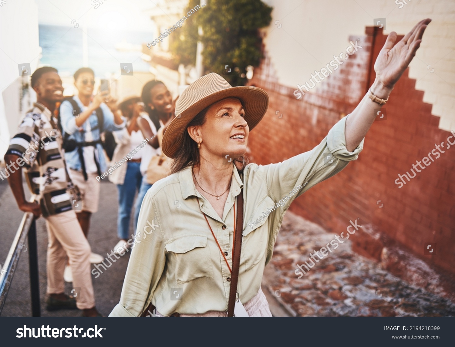Travel, education and a teacher with students on school field trip, on urban tour. Woman, city guide and group of happy tourists, pointing at local architecture and learning on international holiday #2194218399