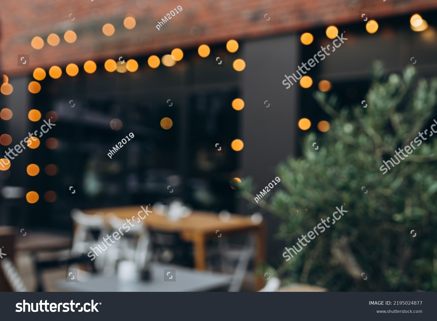 Blurred background of outdoor restaurant with abstract bokeh light. Outdoor cafe with tables and chairs #2195024877