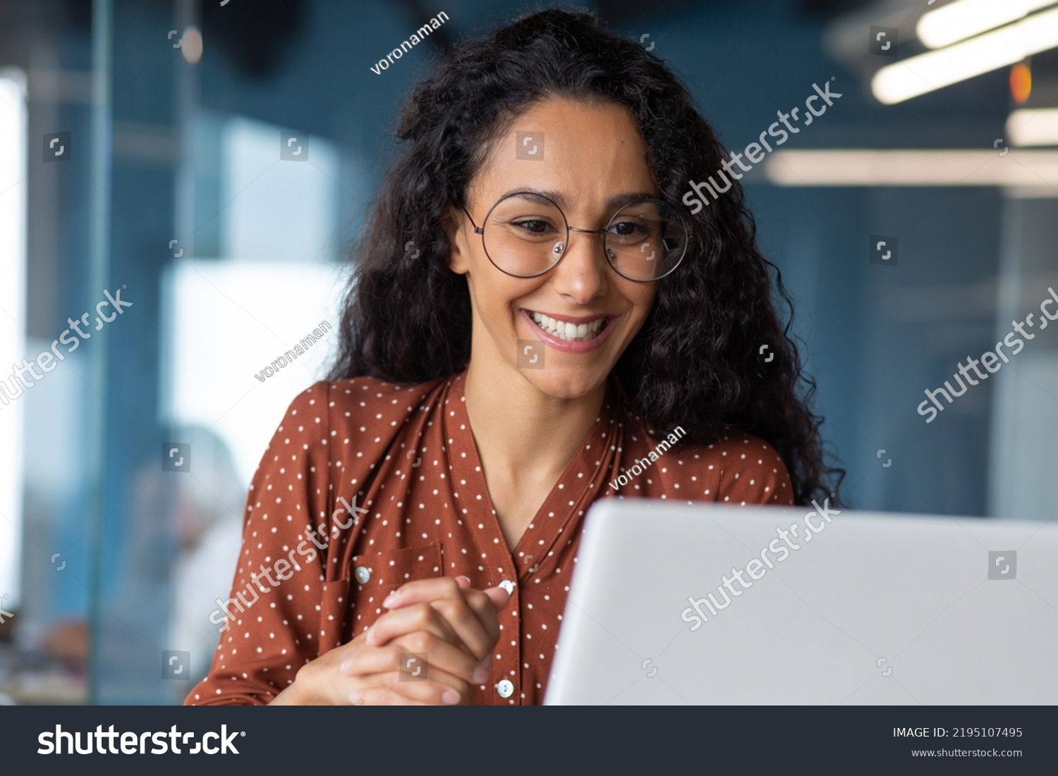 Close-up photo of young beautiful business woman with curly hair and glasses Hispanic woman talking on video call using laptop for remote communication and conference #2195107495