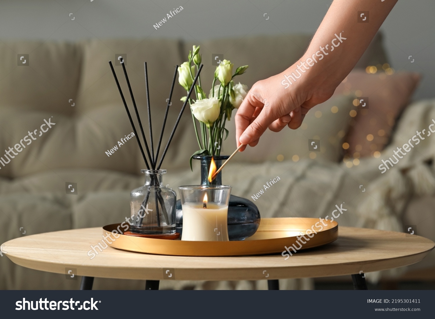 Woman lighting candle at wooden table in living room, closeup #2195301411