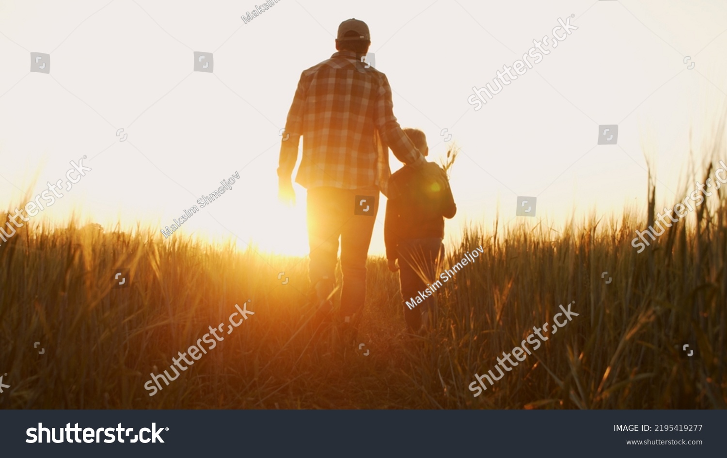 Farmer and his son in front of a sunset agricultural landscape. Man and a boy in a countryside field. Fatherhood, country life, farming and country lifestyle. #2195419277