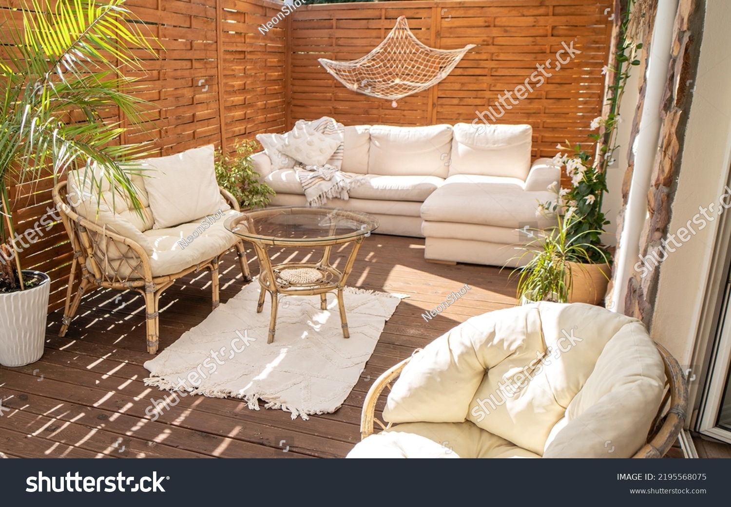 Real photo of relaxing boho zone in home. Wooden floor on terrace with comfy furniture and green plants. Decoration concept. Sunny summer day.
 #2195568075