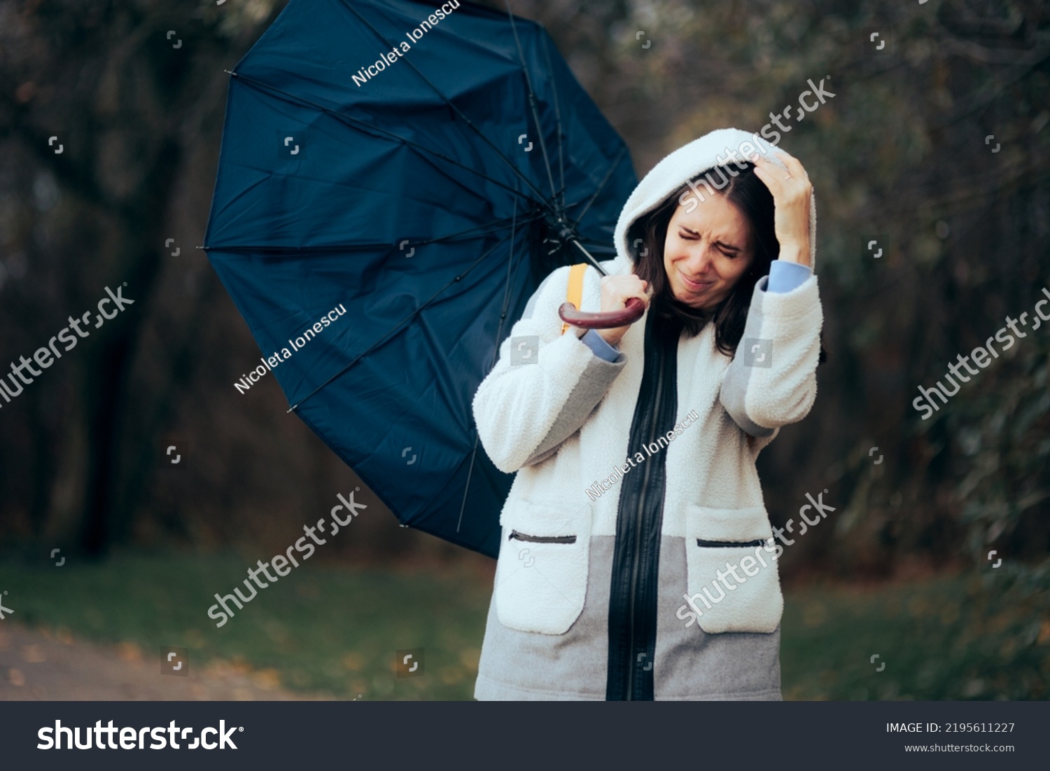 
Woman Struggling During Raining Storm Holding an Umbrella. Unhappy girl fighting windstorms outdoors in nature
 #2195611227