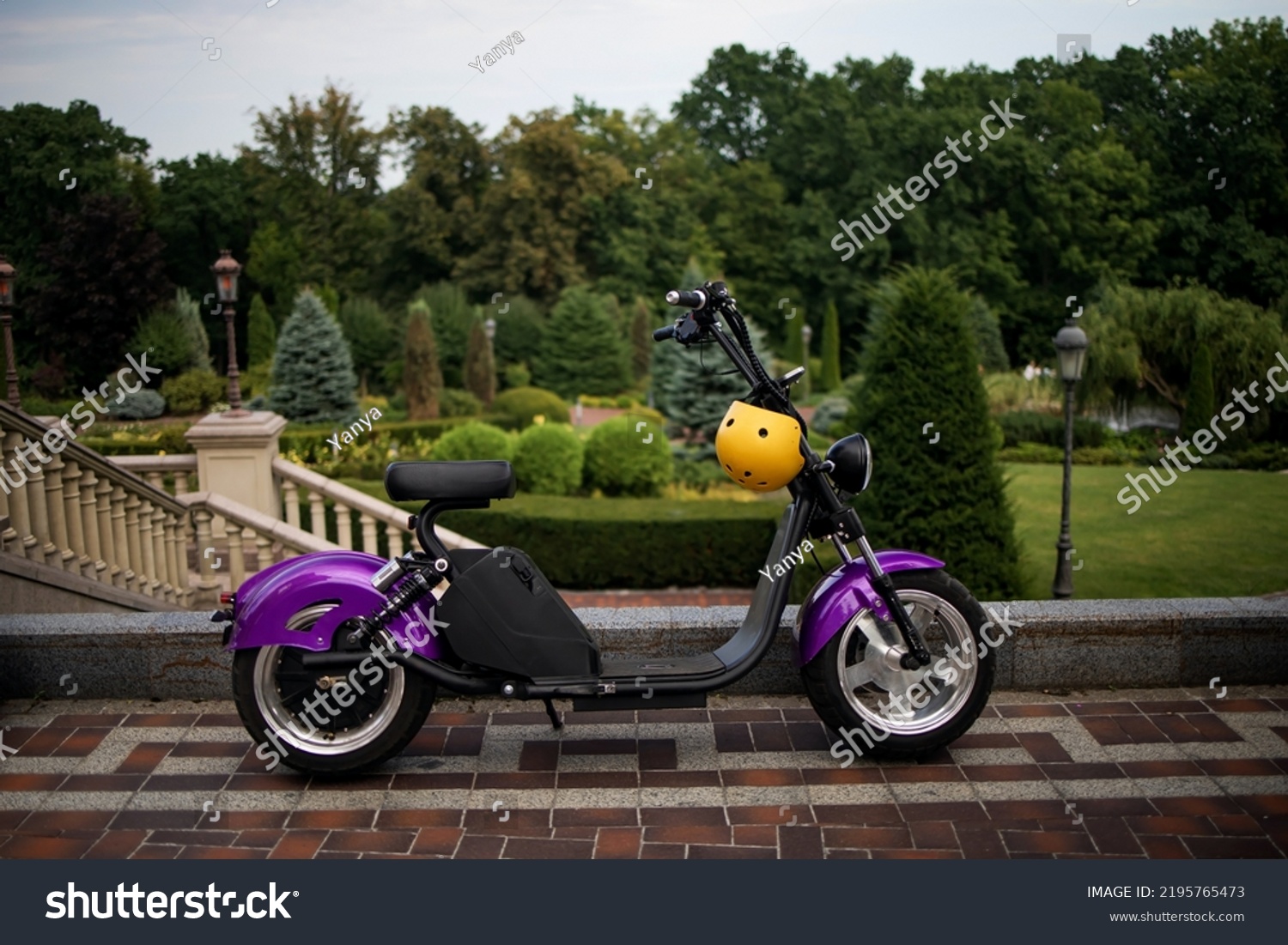 Modern violet electro electric scooter and yellow helmet parking in park #2195765473