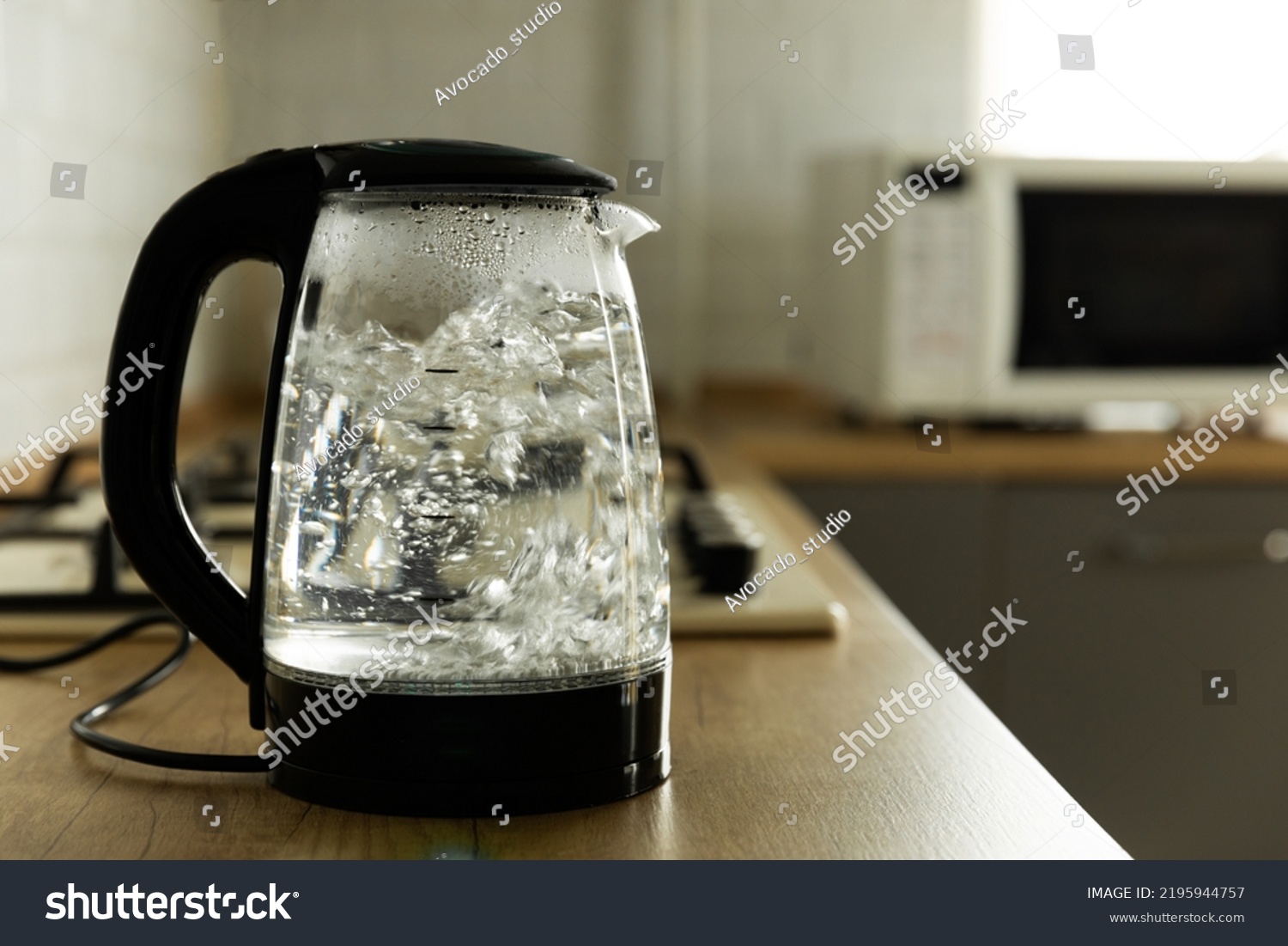 Modern electric transparent kettle on a wooden table in the kitchen.Kettle for boiling water and making tea.Home appliances for making hot drinks.Space for copy.Place for text. #2195944757
