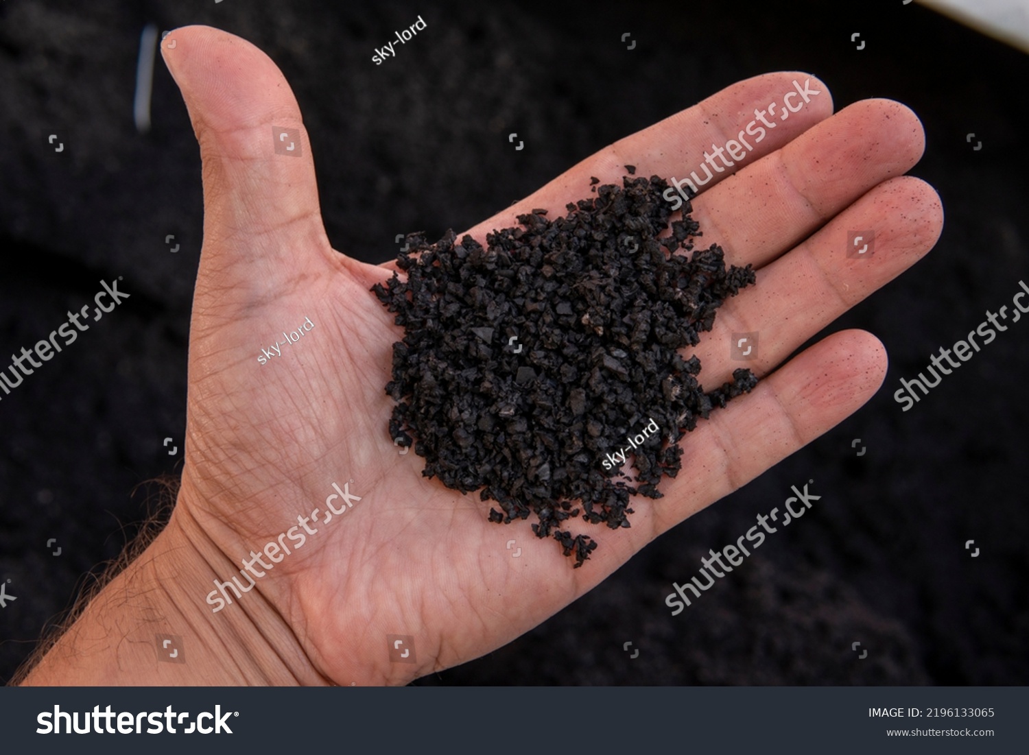 Recycled rubber in hand. Rubber crumb obtained in the process of recycling used car tires used for flooring sports and playgrounds. #2196133065