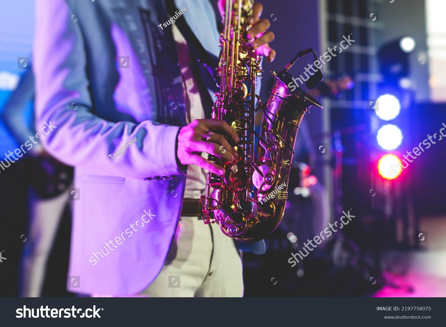 Concert view of saxophonist, a saxophone sax player with vocalist and musical band during jazz orchestra show performing music on stage in the scene lights
 #2197758075