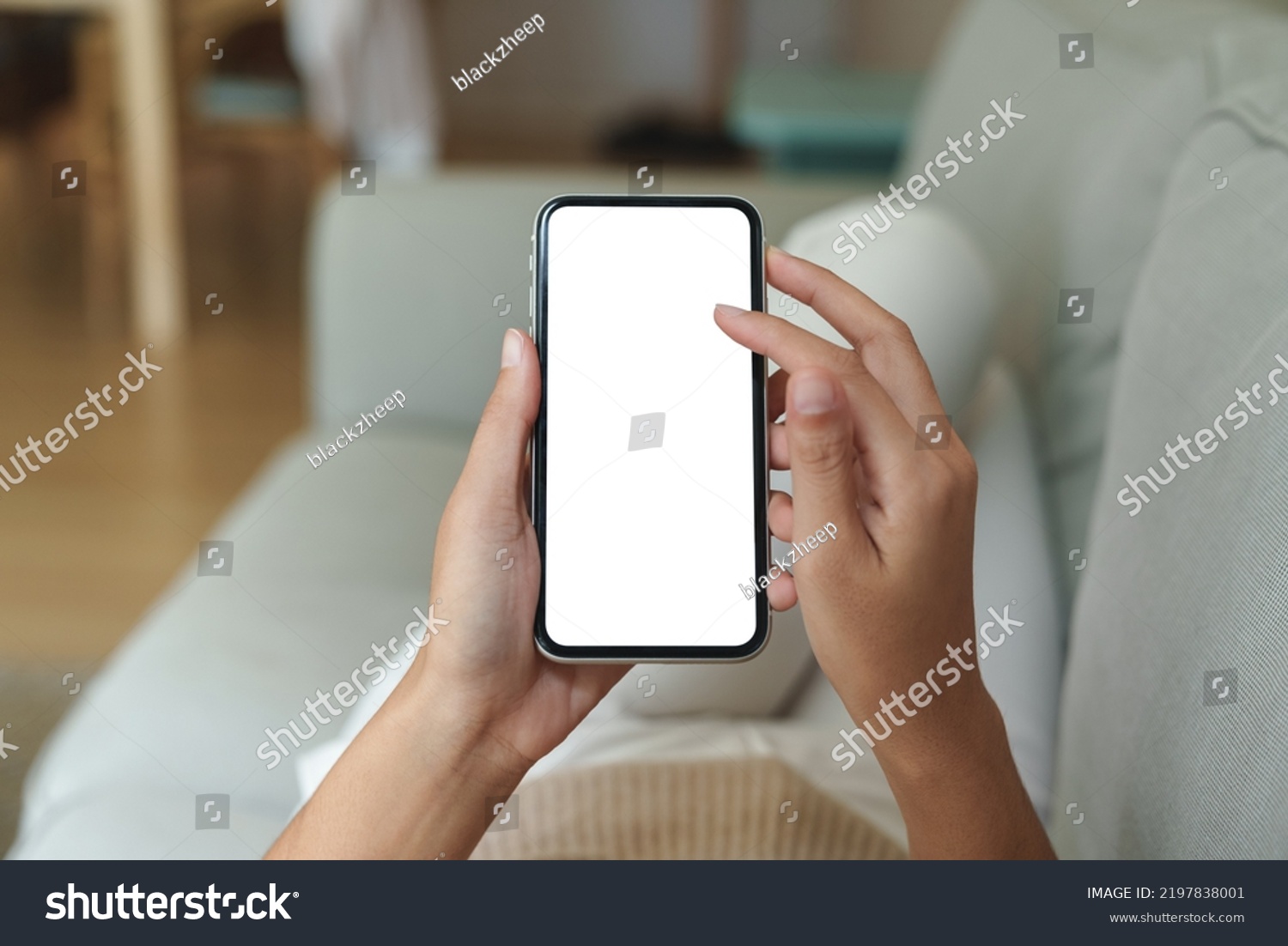 close-up hand using phone showing white screen in living room #2197838001
