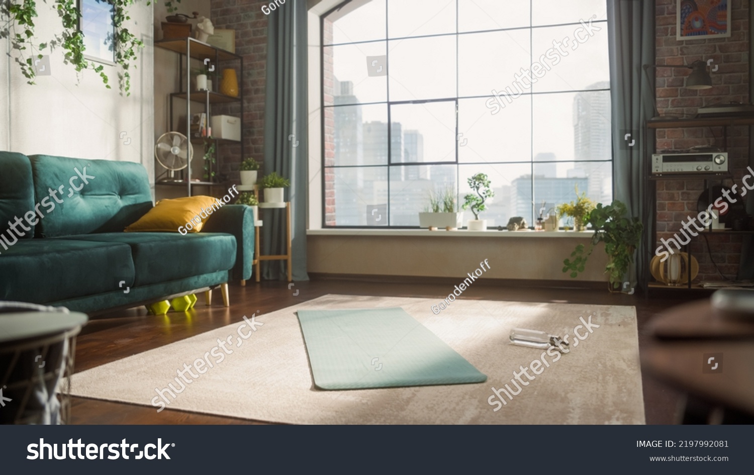 Empty Stylish Loft Apartment With Big Window. Sun Shinning on Spacious and Bright Living Room With Yoga Mat and Bottle of Water Laying on the Floor. Preperation For Online Workout Concept. #2197992081