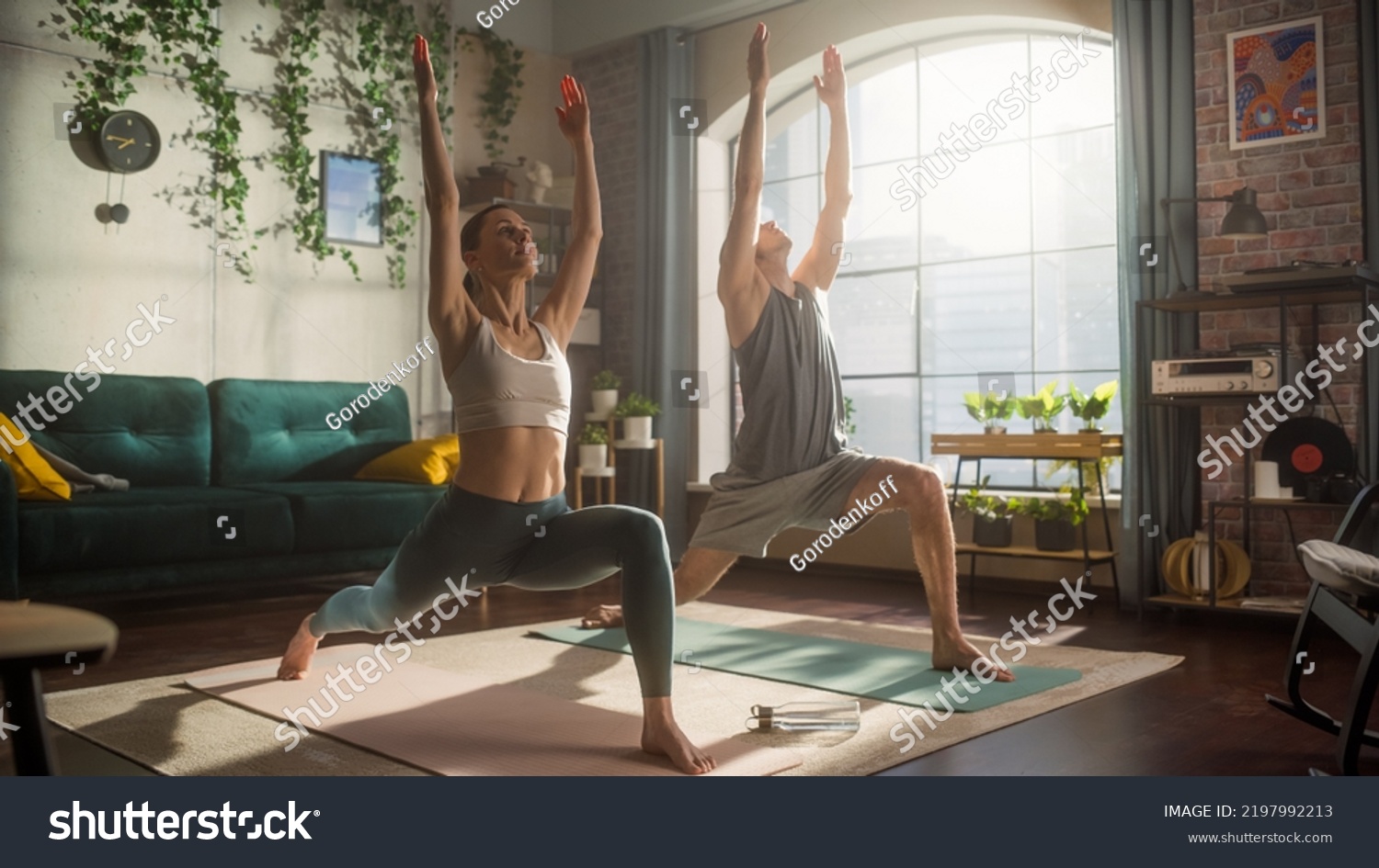 Athletic Young Couple Exercising Together, Stretching and Doing Yoga in the Morning in Bright Sunny Room at Home. Beautiful Man and Woman in Sports Clothes Practising Different Asana Poses on the Mat. #2197992213