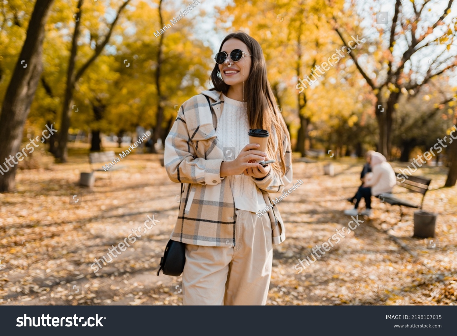 attractive young woman walking in autumn park with coffee wearing checkered coat, sunglasses, happy mood, fashion style trend #2198107015