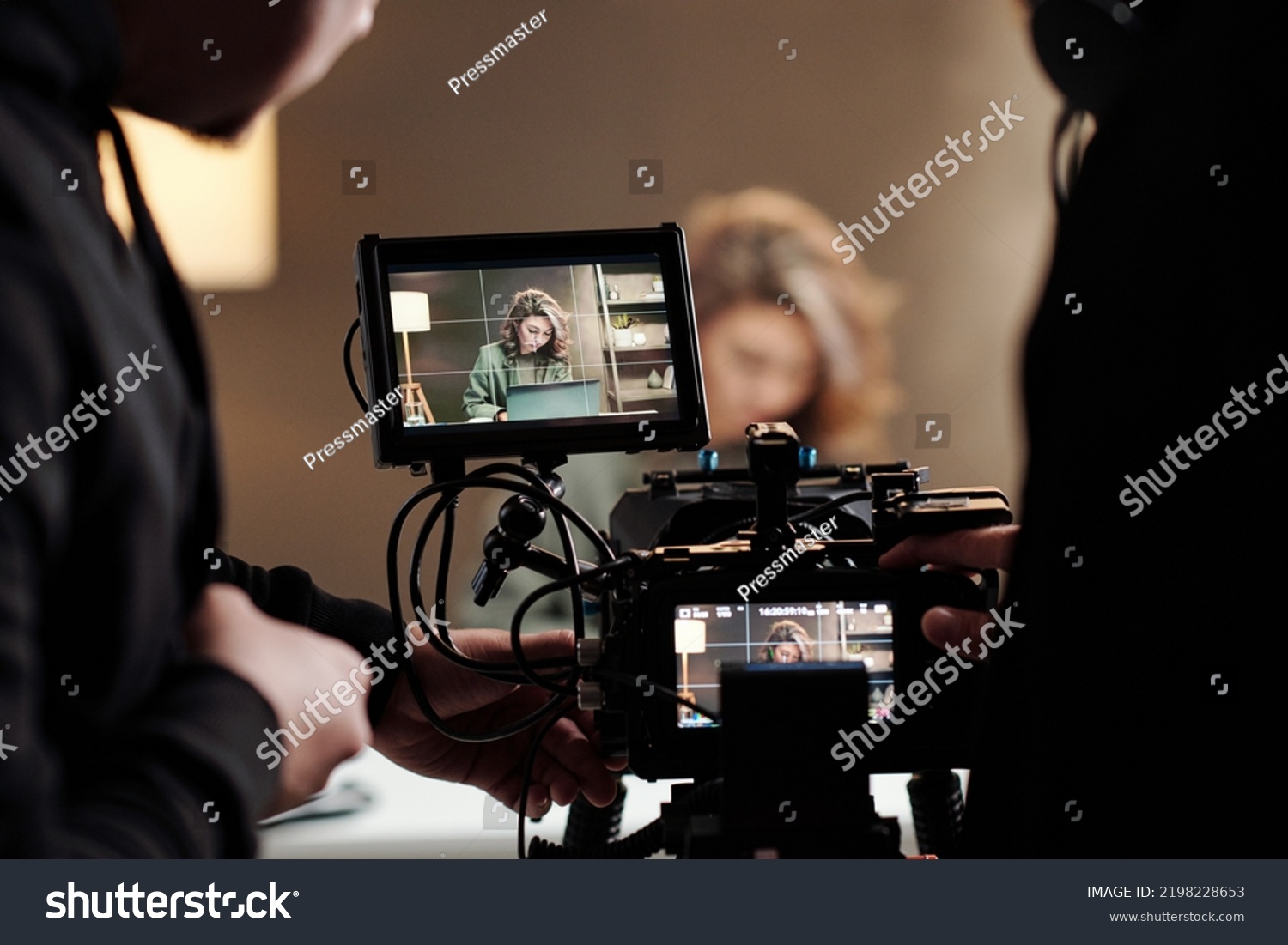 Close-up of steadicam screens with female model using laptop by table during commercial being shot by cameraman and his assistant #2198228653