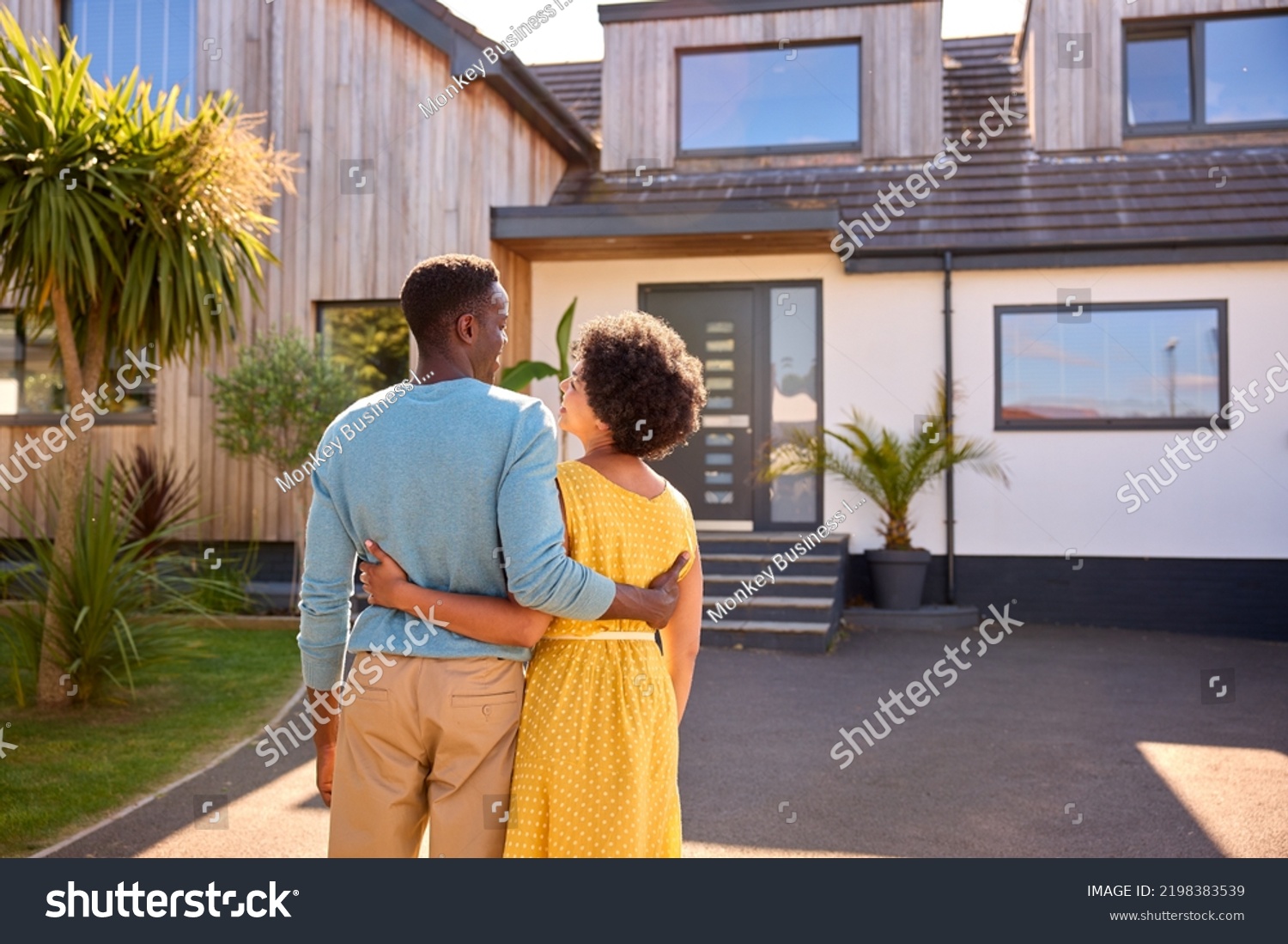 Rear View Of Couple Standing In Driveway In Front Of Dream Home Together #2198383539