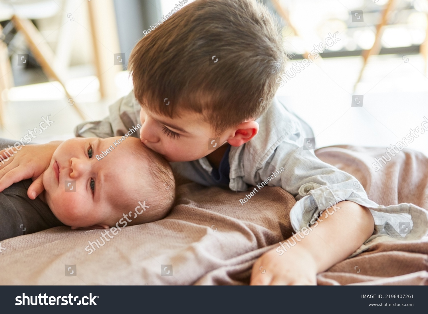 Little boy as big brother gives baby a kiss on the forehead for love and affection #2198407261
