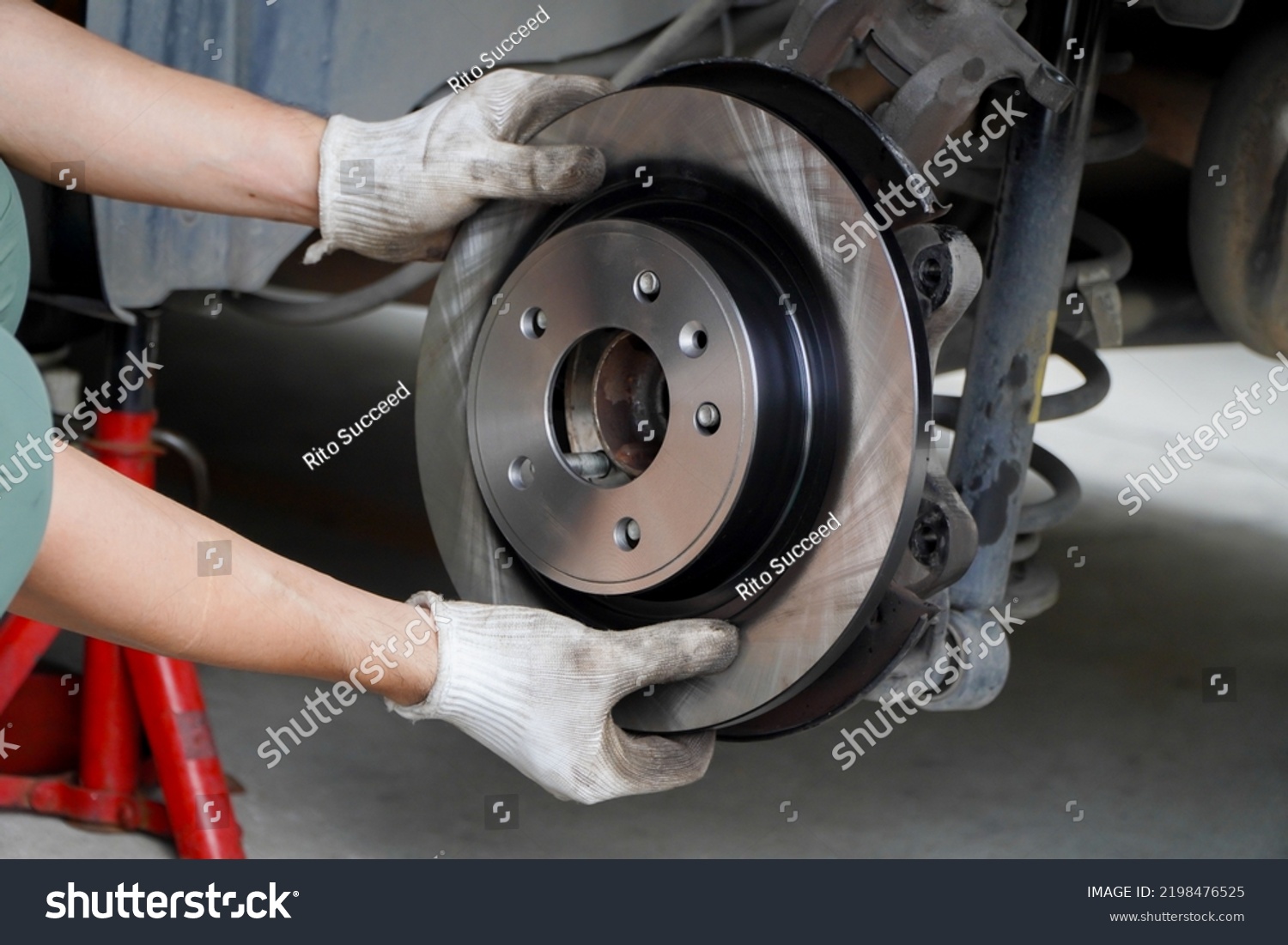 Asian mechanic replaces new brake discs in garage cars. #2198476525