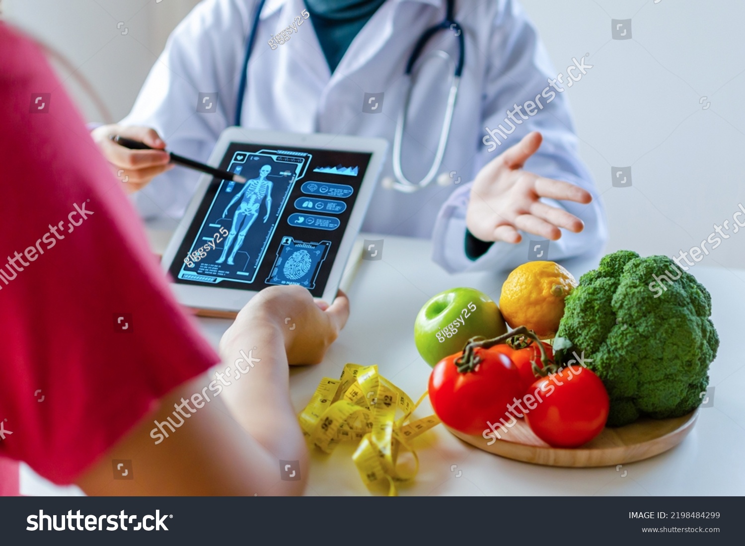 nutritionist female doctor using digital mobile tablet with virtual graphic icon diagram and vegetable and fruit with patient on desk at office hospital, nutrition, food science, healthy food concept #2198484299
