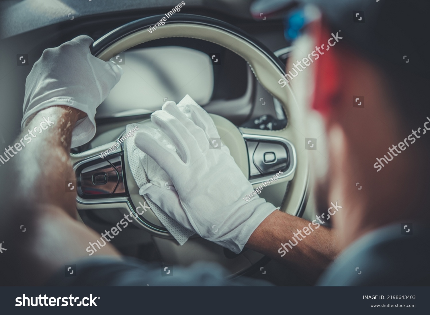 Closeup of Leather Steering Wheel in Modern Vehicle Being Cleaned by Professional Auto Detailer with the Use of Special Fluid-Saturated Wipes. Professional Car Detailing Services Theme. #2198643403