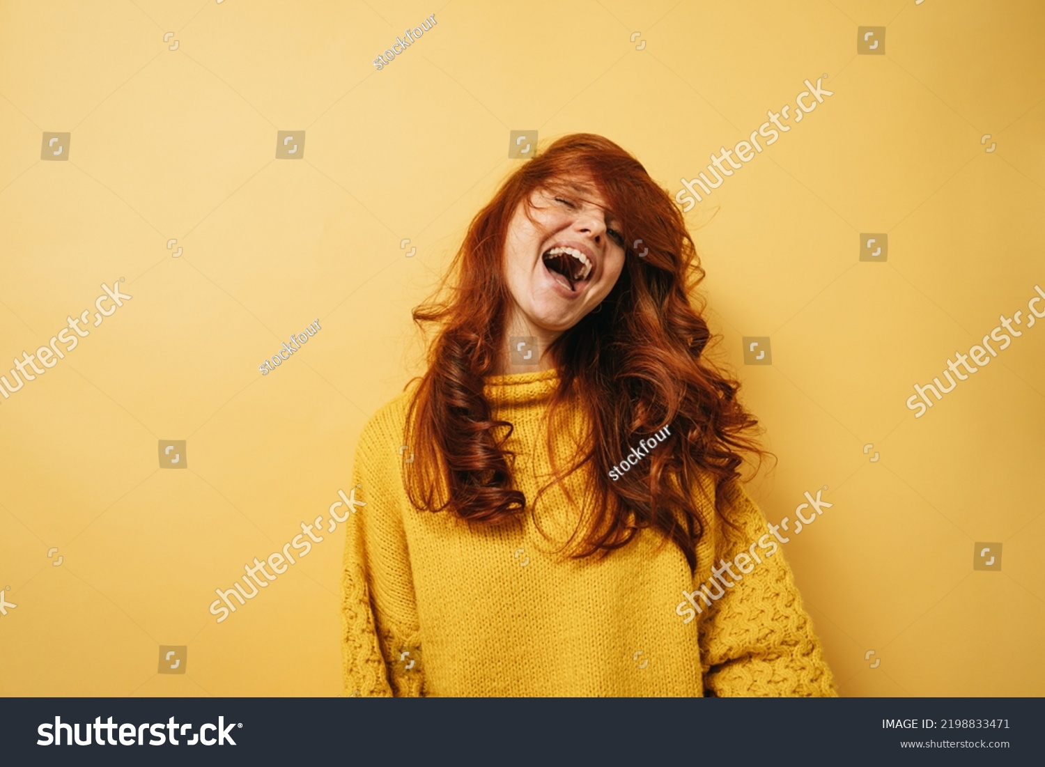 Laughing redhead woman with yellow sweater is happy copyspace against yellow background #2198833471