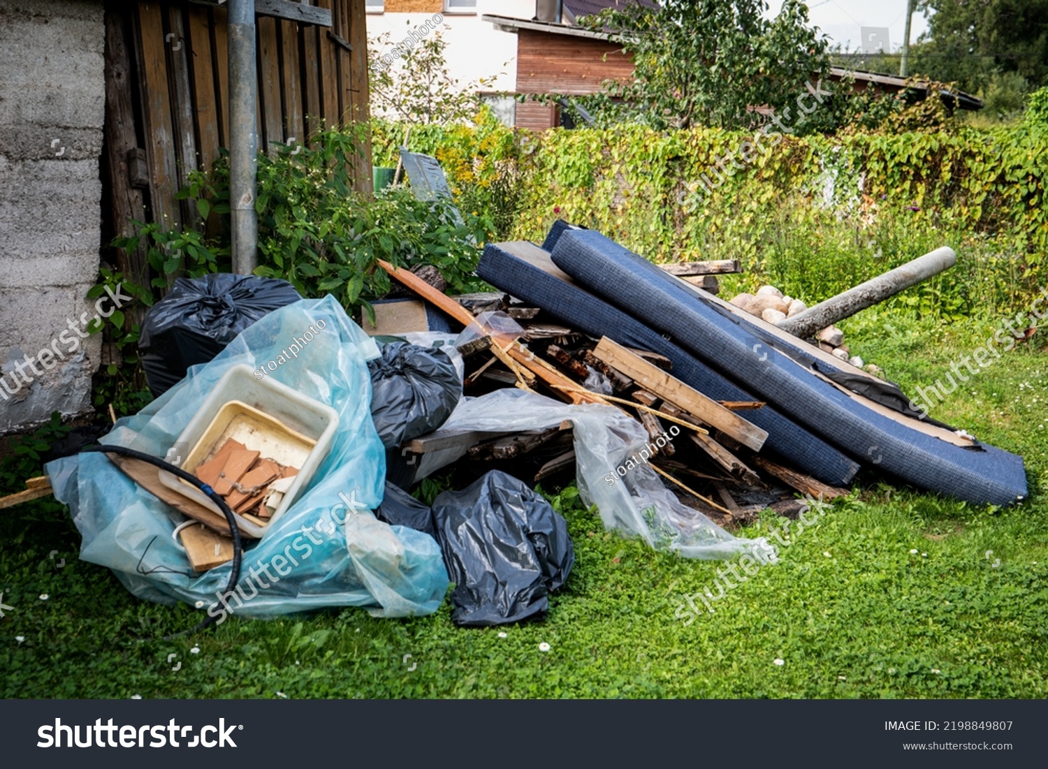 Garbage and a pile of construction debris in the yard of a house. #2198849807