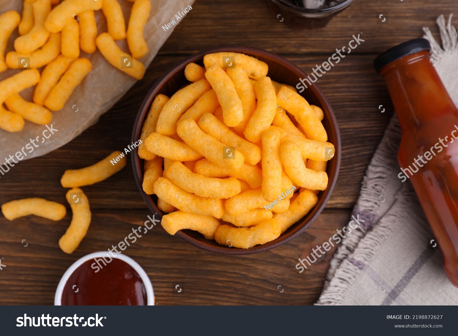 Crunchy cheesy corn snack and ketchup on wooden table, flat lay #2198872627