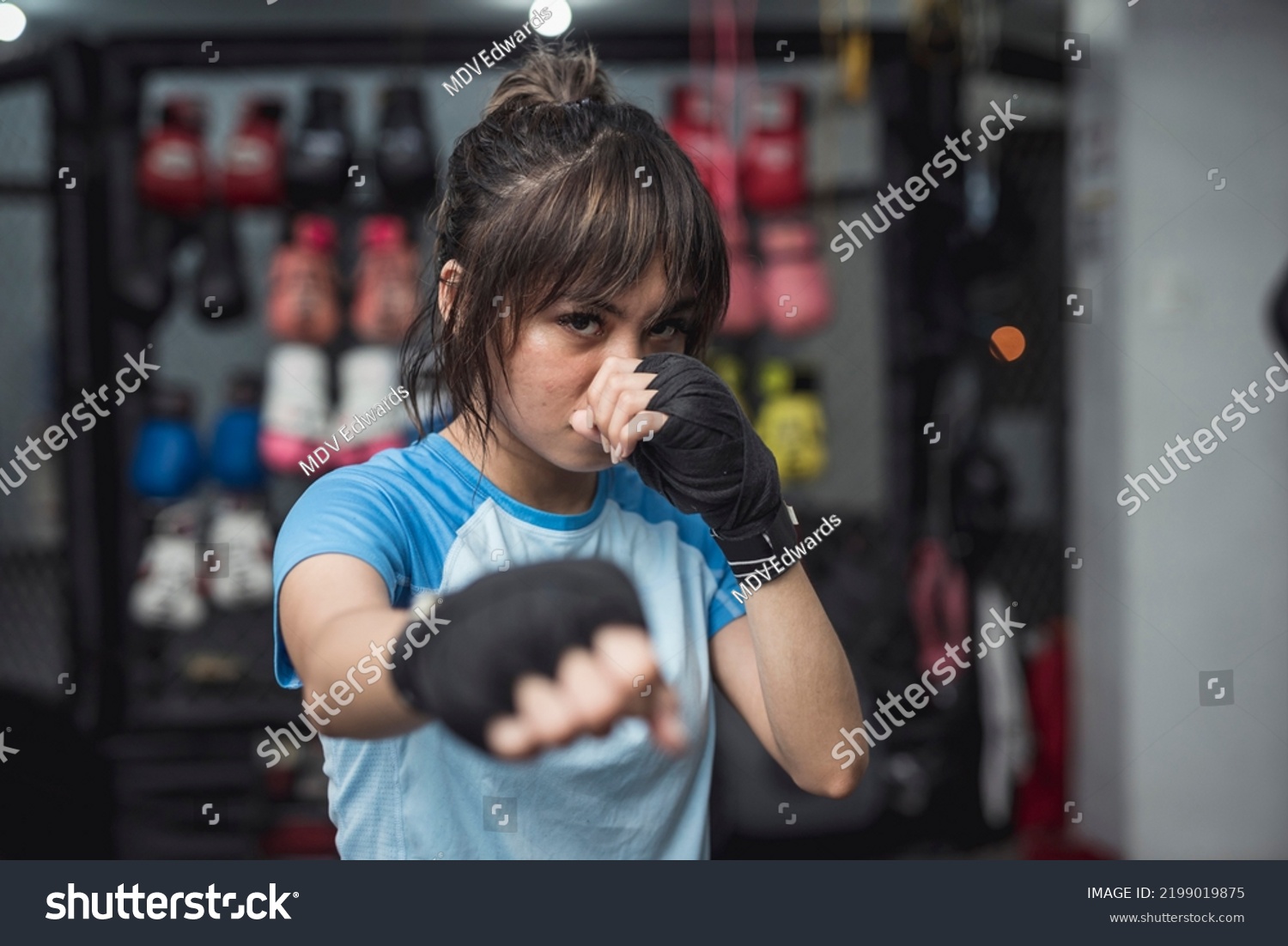 A young mixed martial arts athlete fiercely poses for the camera while demonstrating the proper fighting stance in throwing a punch. #2199019875