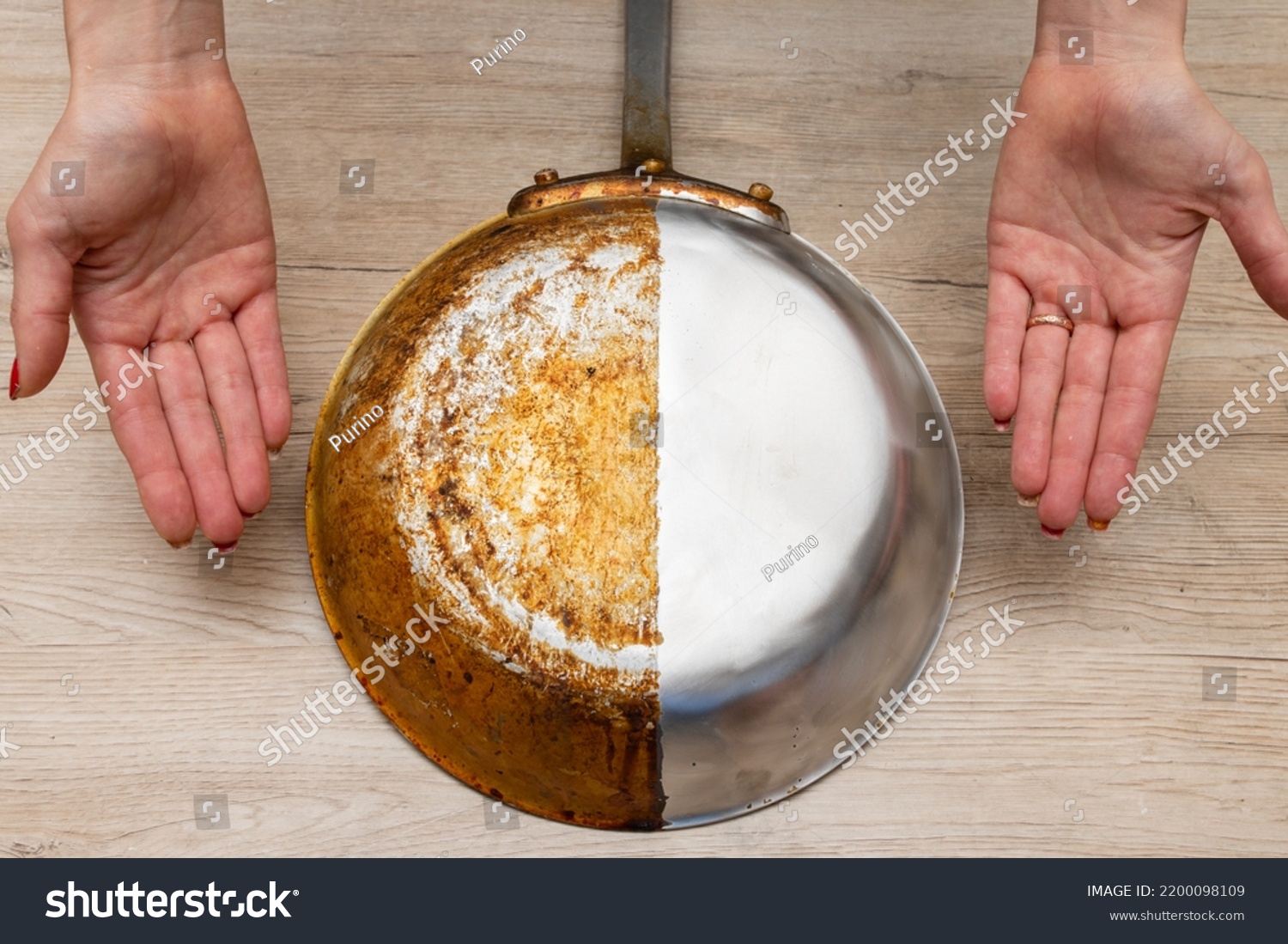 A woman's hand presenting a frying pan that is half burnt and half polished #2200098109