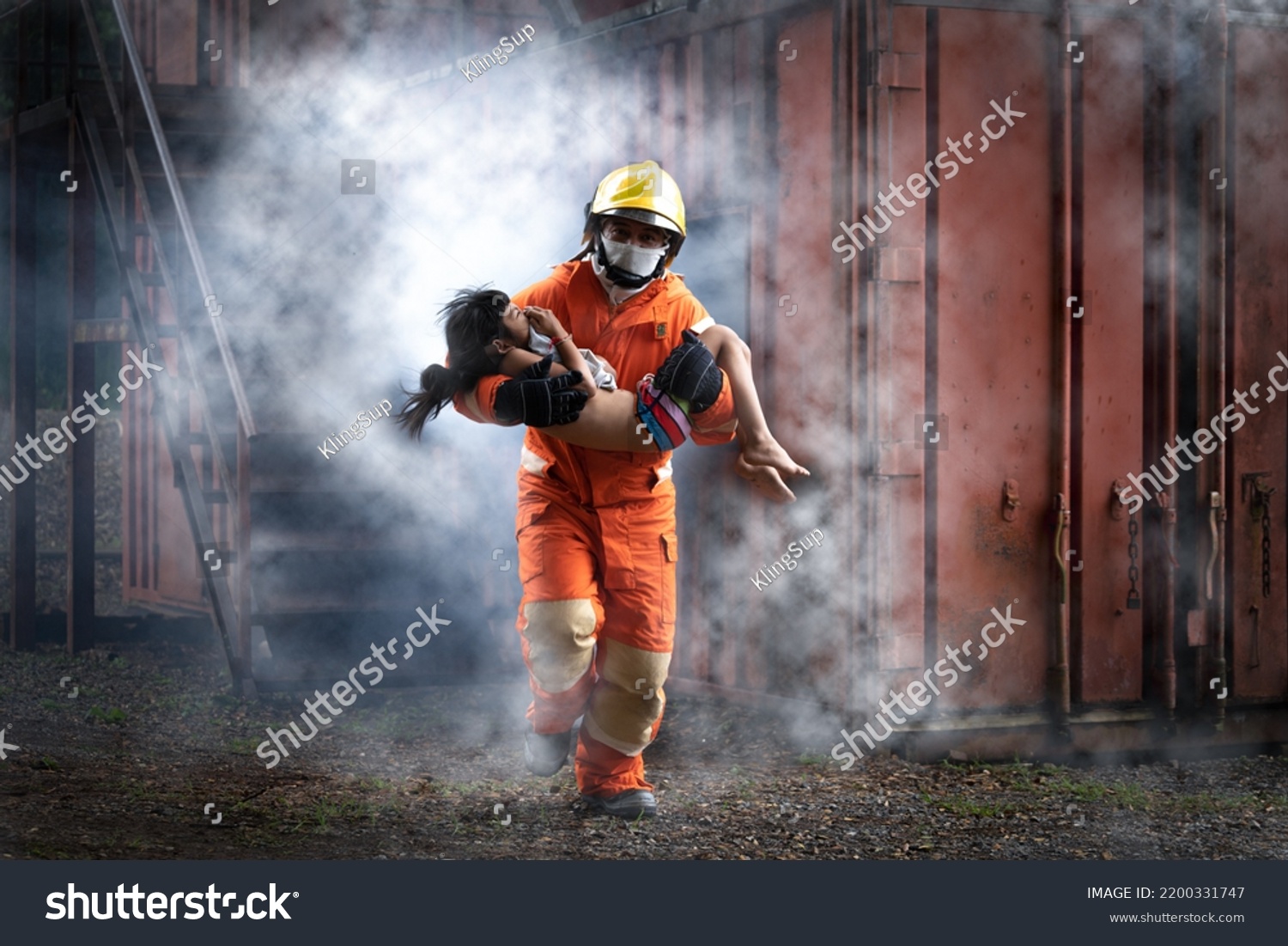 Firefighter man help Asian little girl from out container with smoke from fire.Firefighter rescue team training help people from fire accident simulation. #2200331747