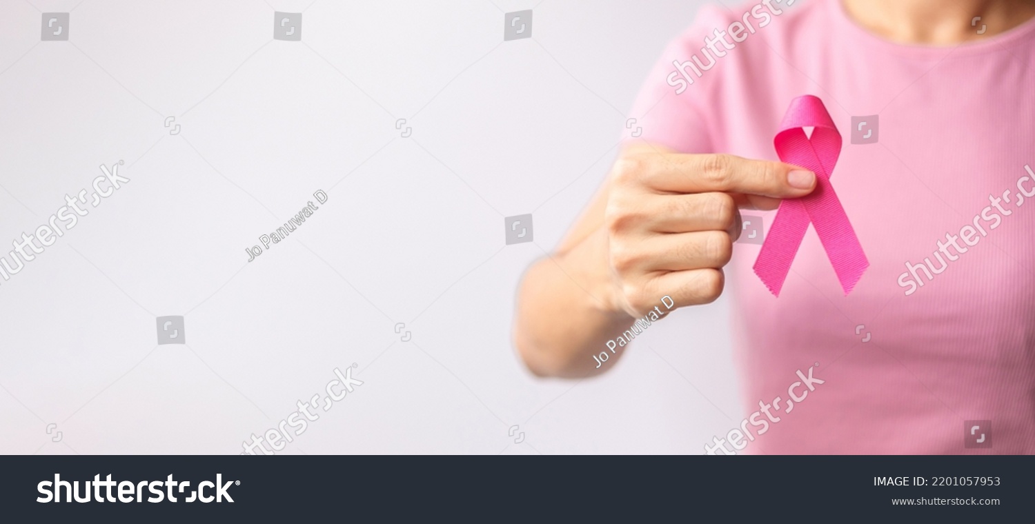 Pink October Breast Cancer Awareness month, woman hand hold pink Ribbon and wear shirt for support people life and illness. National cancer survivors month, Mother and World cancer day concept #2201057953