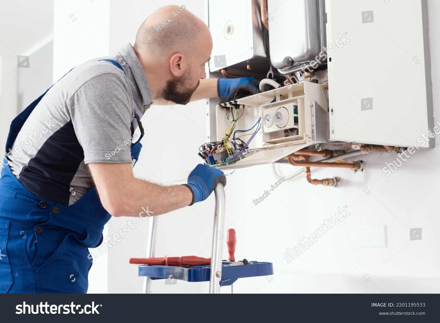 Professional boiler service: qualified technician checking a natural gas boiler at home #2201195533