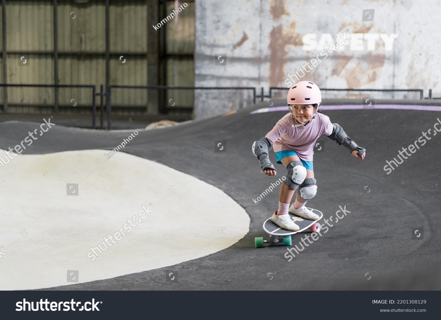 asian child skater or kid girl fun playing skateboard or ride surf skate and turn on pump track in skate park by extreme sports to wearing helmet elbow pads wrist knee support for body safety protect #2201308129