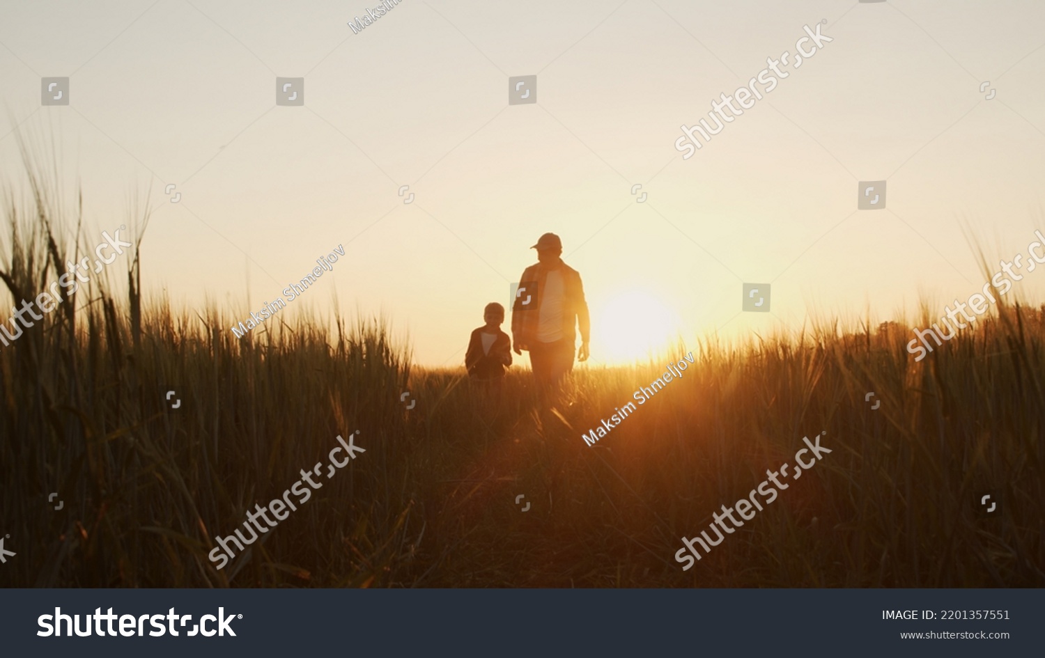 Farmer and his son in front of a sunset agricultural landscape. Man and a boy in a countryside field. Fatherhood, country life, farming and country lifestyle. #2201357551
