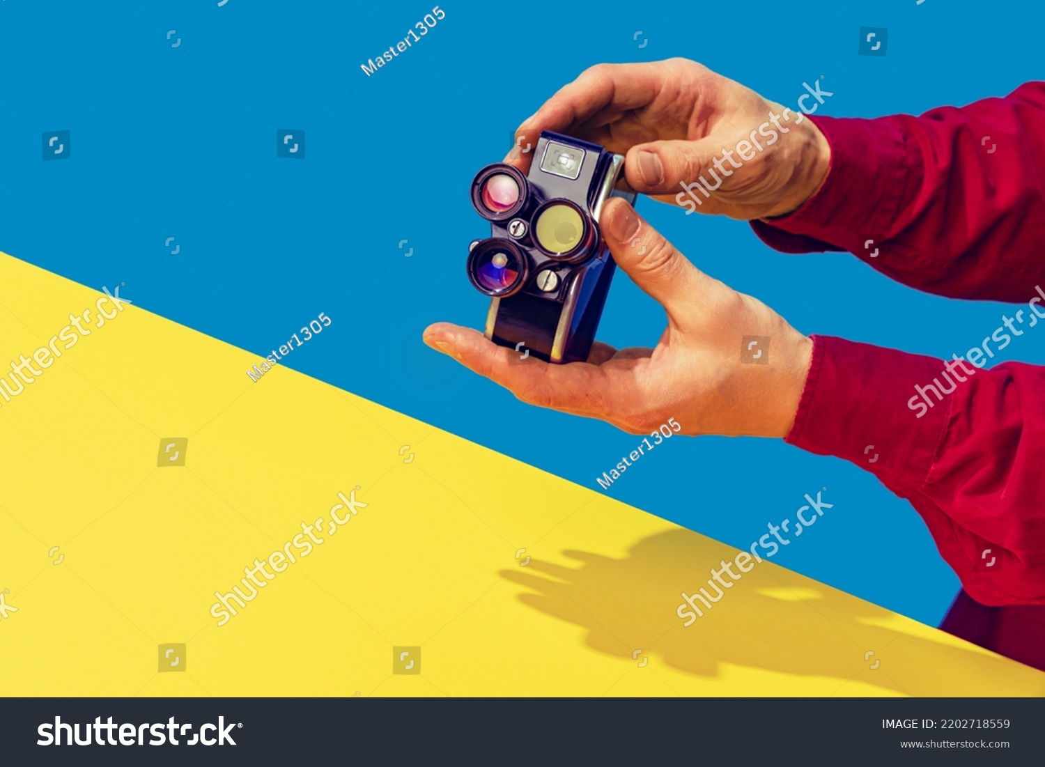 Pop art photography. Colorful image of retro photo camera on bright yellow tablecloth isolated over blue background. Concept of art culture, vintage things, mix old and modernity. Copy space for ad #2202718559