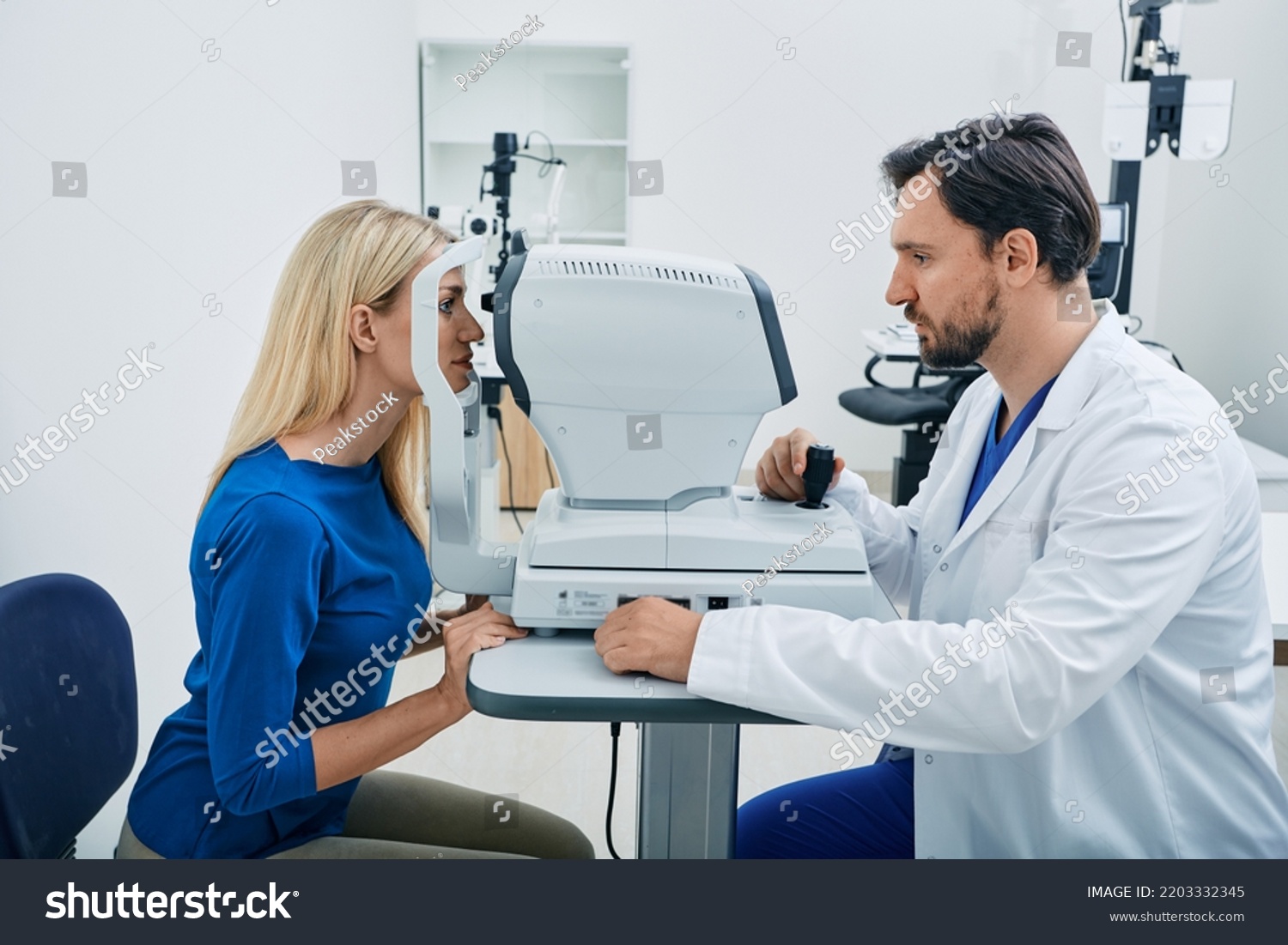 Experienced ophthalmologist man using automated refractor for vision correction female patient in ophthalmic office #2203332345