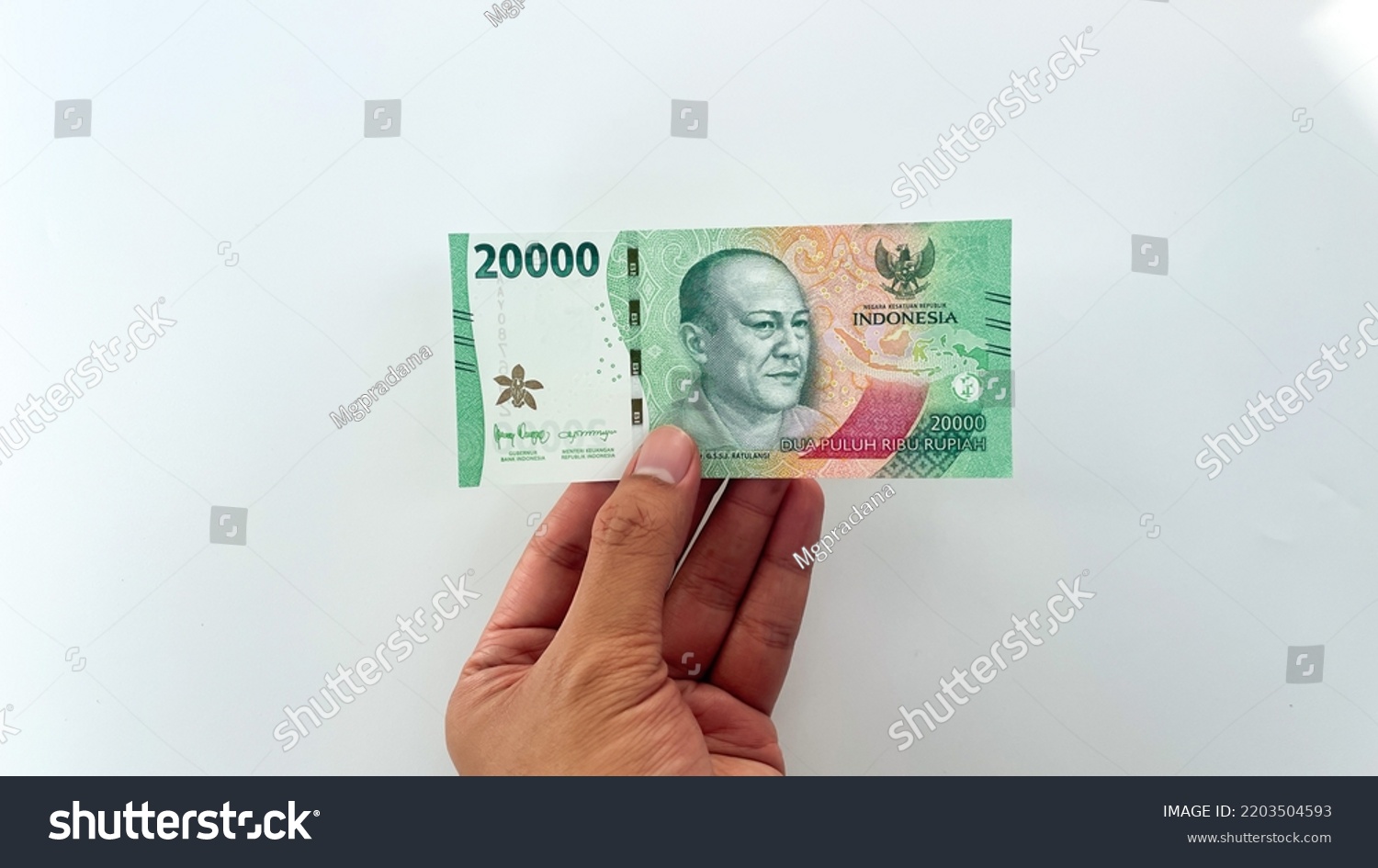 male hand holding new rupiah banknote in 2022. new 20,000 or twenty thousand rupiah denomination isolated on white background #2203504593