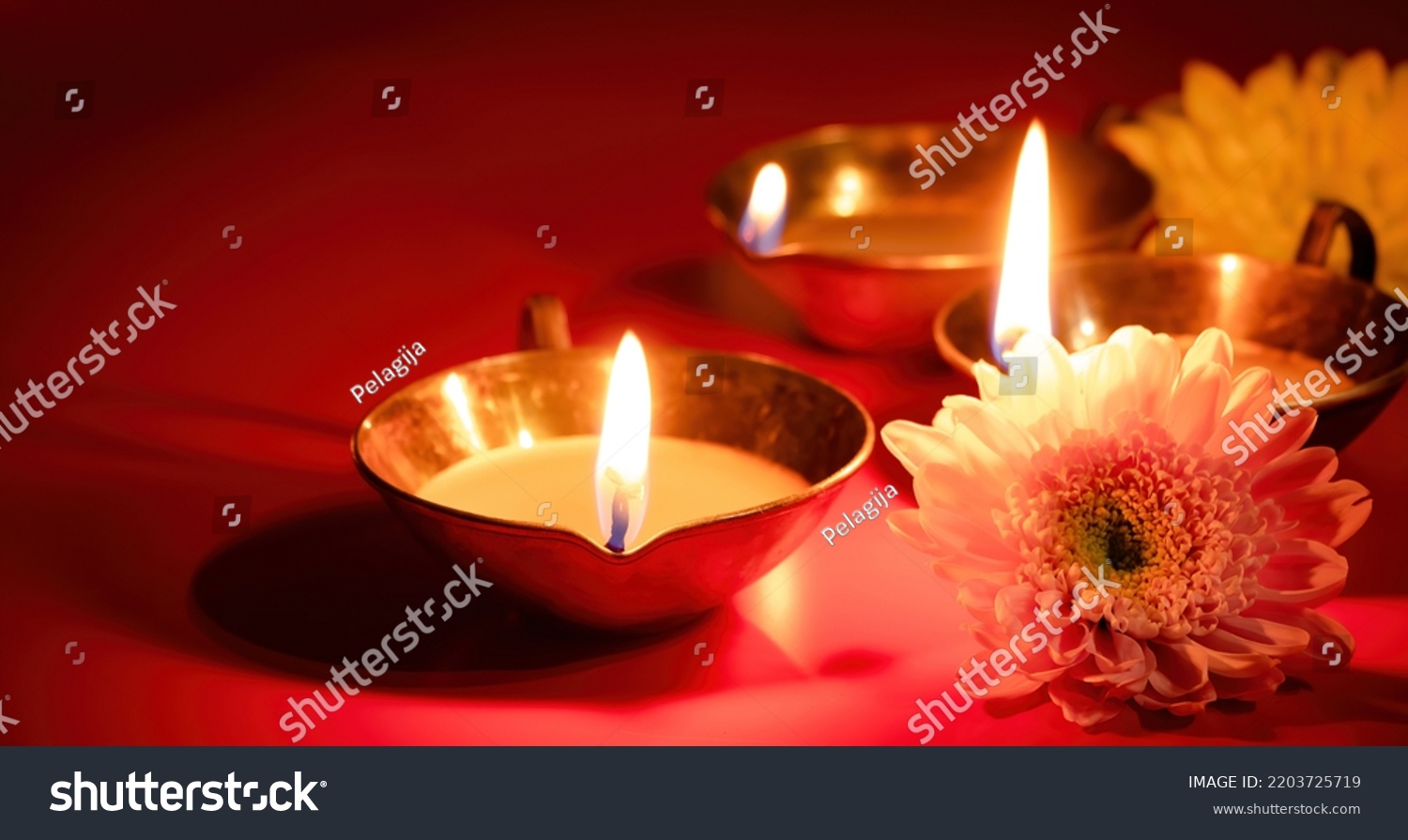 Happy Diwali. Diya oil lamp and flowers on red background. Traditional Hindu celebration. Religious holiday of light. Copy space, banner format. #2203725719