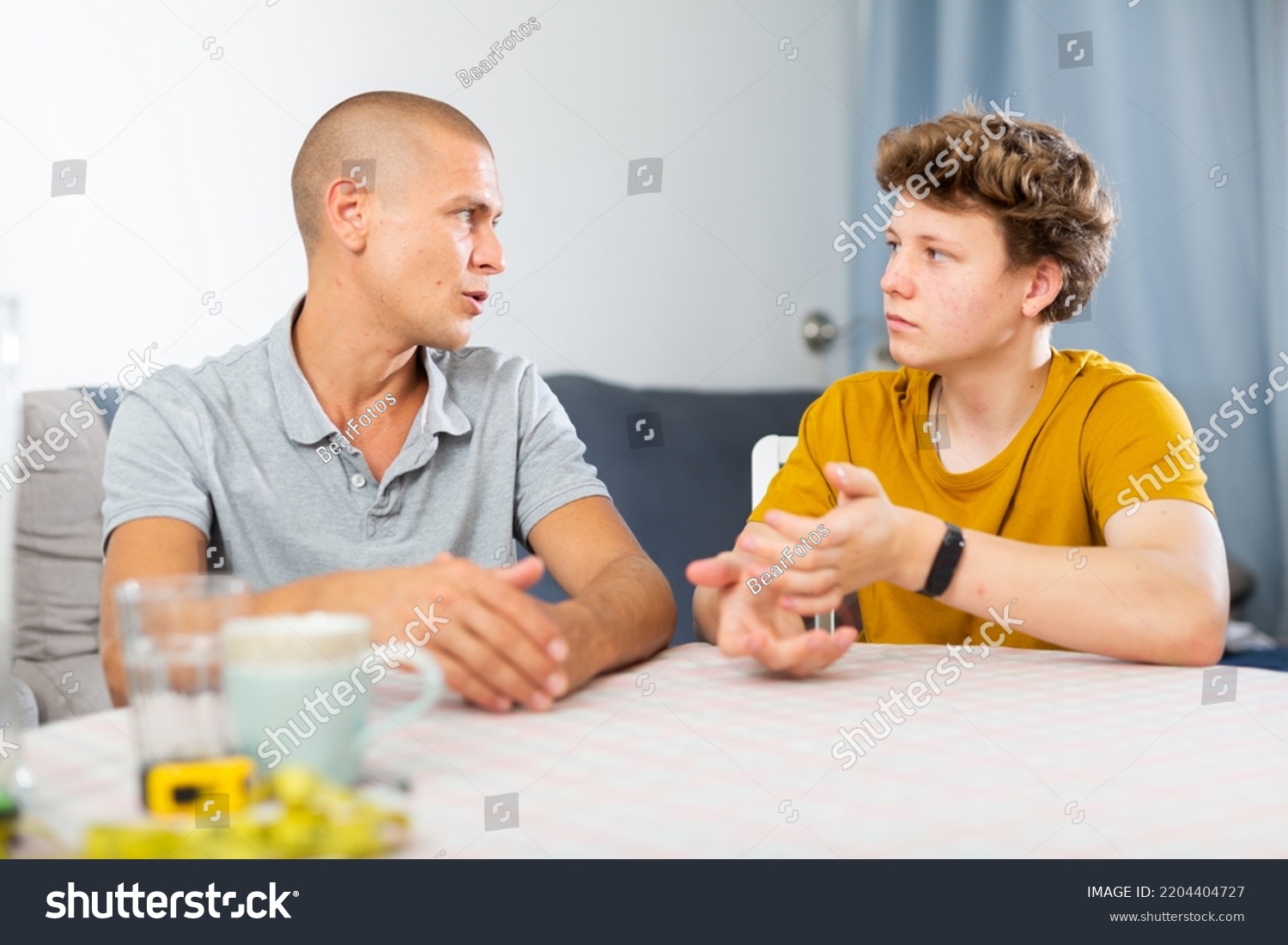 Father and his young son talking about something while sitting at the table #2204404727