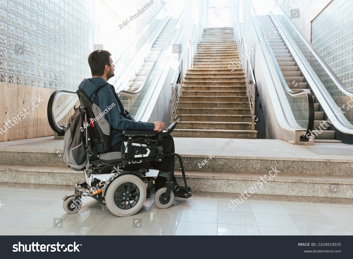 Man with disability on wheelchair stopped in front of staircase, raising awareness of architectural barriers and accessibility issues #2204819035