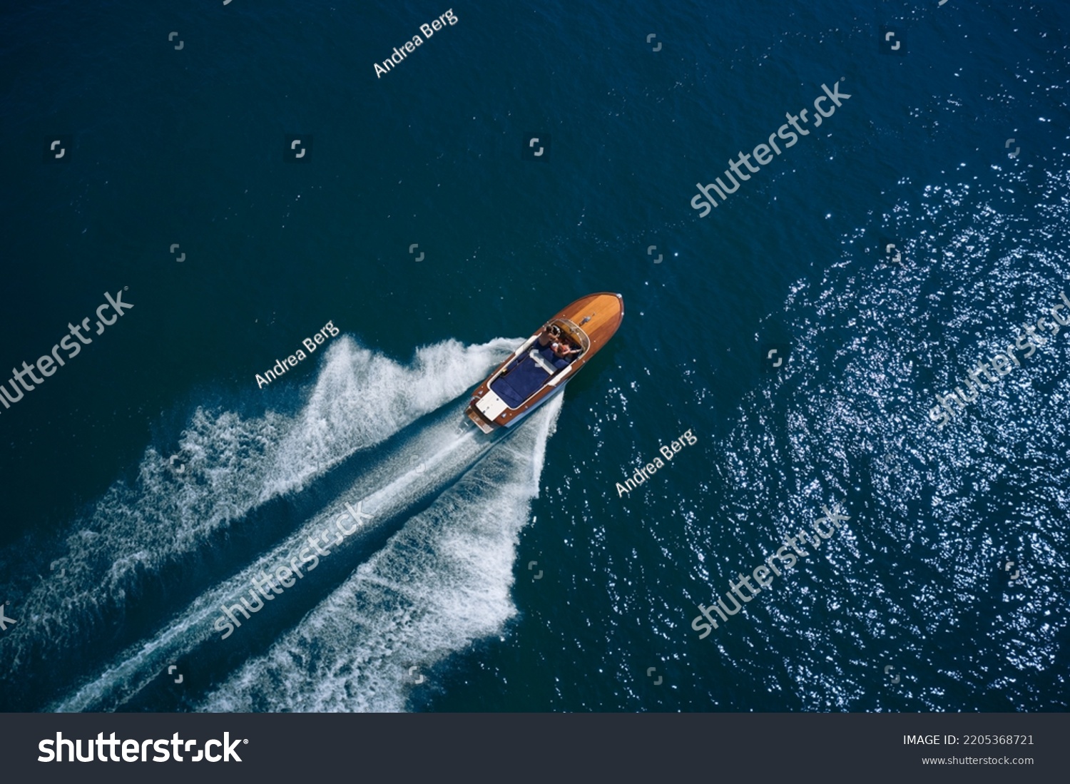 Luxurious wooden motor boat rushes through the waves of the blue Sea. Classic Italian wooden boat fast moving aerial view. Luxurious wooden boat fast movement on dark water. #2205368721