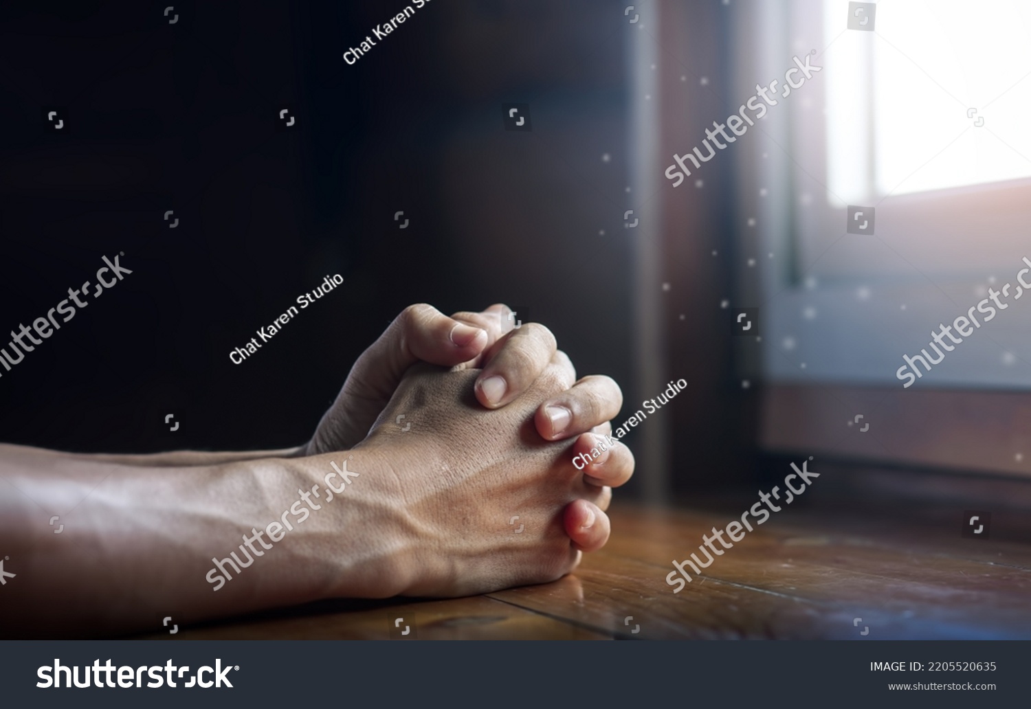 Hands folded in prayer on wooden table with miracle light in church, concept for faith, spirituality and religion, with copy space , space for text #2205520635