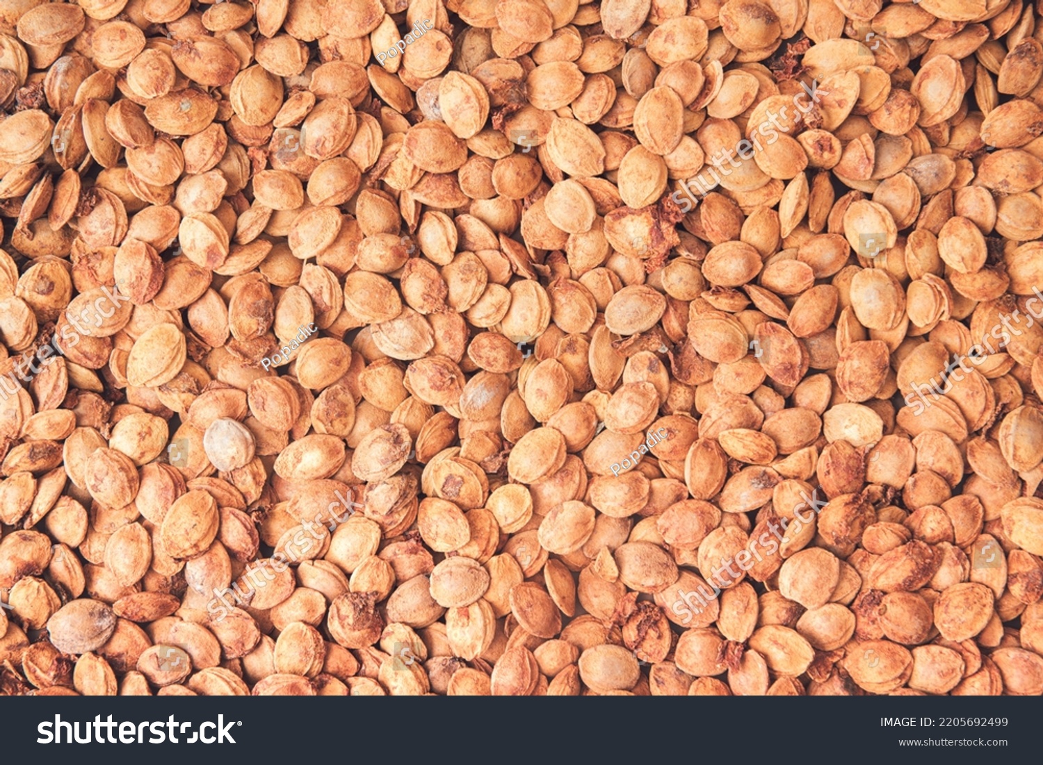 Apricot kernels background. Minimal fruit concept with kernels. A heap of apricot pits, apricot kernels oil. Organic fruit wallpaper. Organic fruit seeds. Flat lay. Healty food. #2205692499