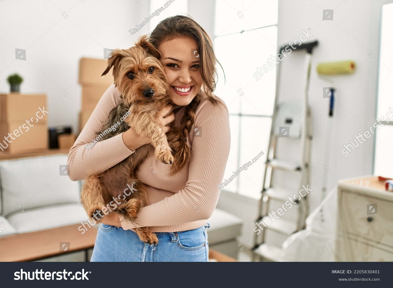 Young beautiful hispanic woman smiling confident hugging dog at new home #2205830401