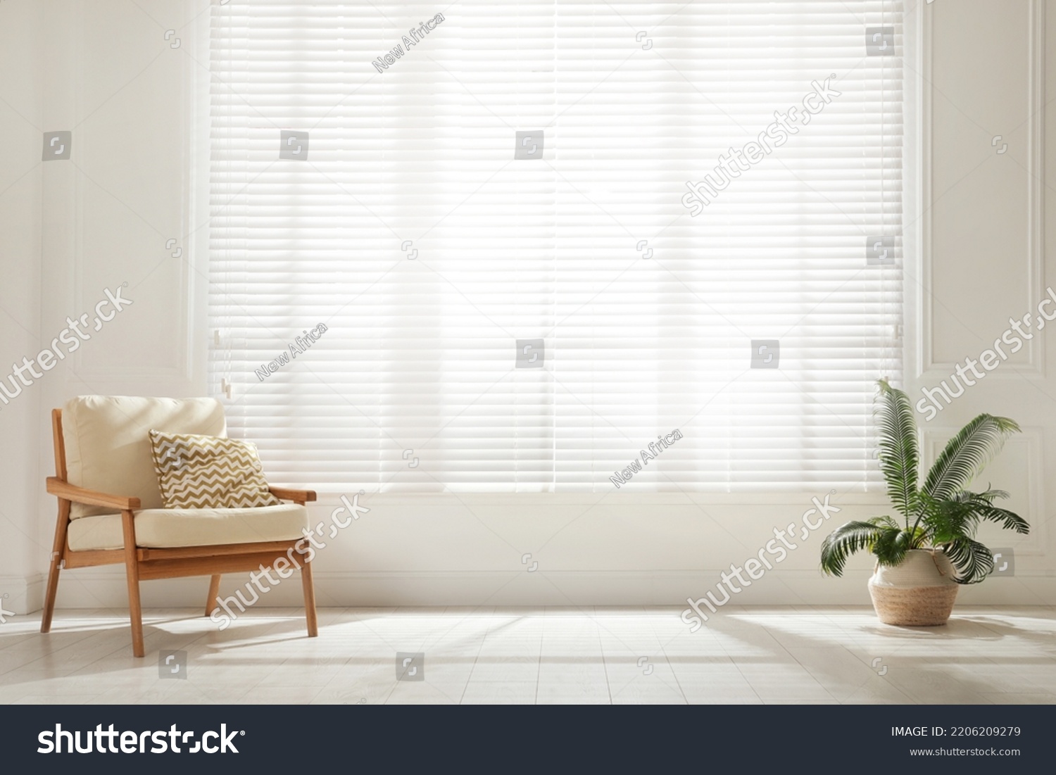 Soft armchair and houseplant near large window with blinds in spacious room. Interior design #2206209279