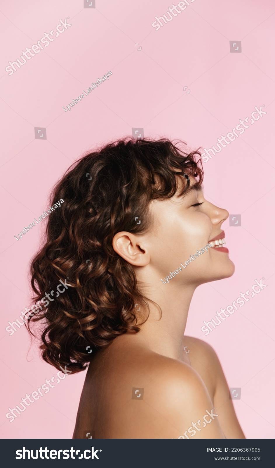 Profile photo of young female model, curly hair, closed eyes, laughing, advertising of skin care treatment, cosmetic and spa product on pink background. #2206367905