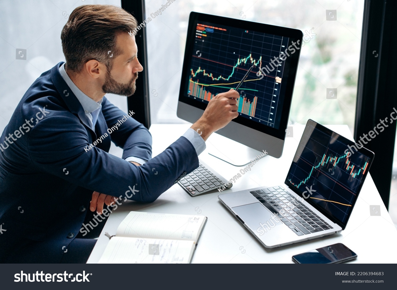Focused smart successful caucasian male stock investor, broker, sits at his work desk, uses computer and laptop, concentrated analyzes risks and prospects, rise or fall of cryptocurrency coin #2206394683