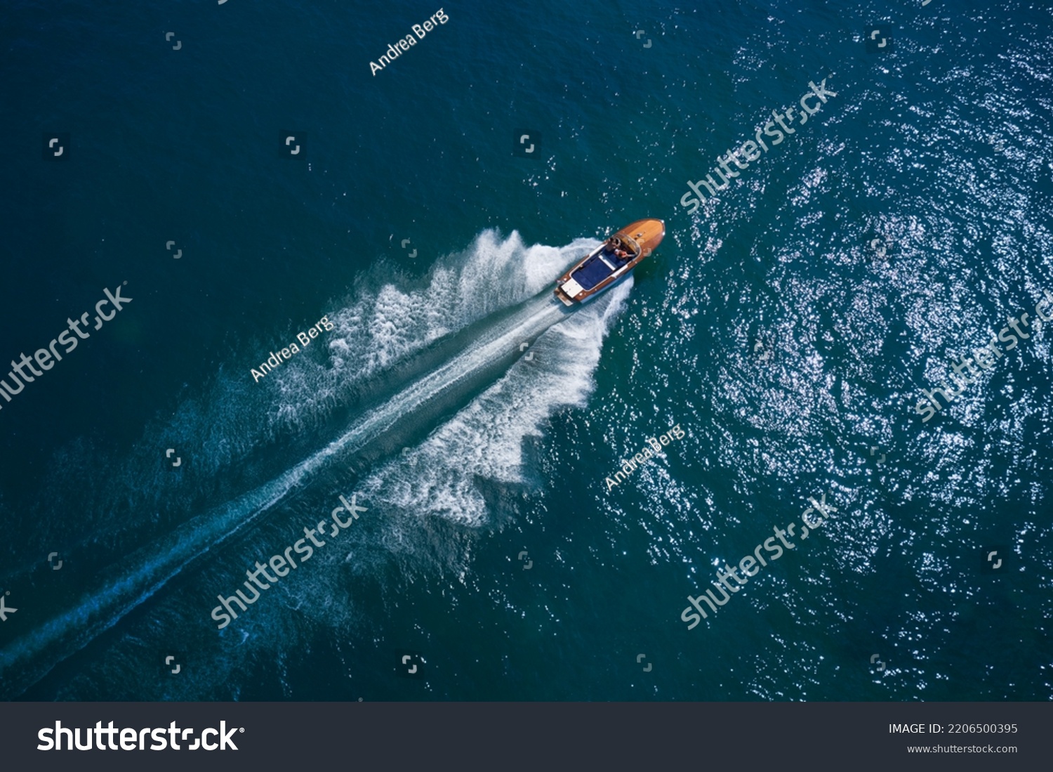 Classic Italian wooden boat fast moving aerial view. Luxurious wooden boat fast movement on dark water. Luxurious wooden motor boat rushes through the waves of the blue Sea. #2206500395