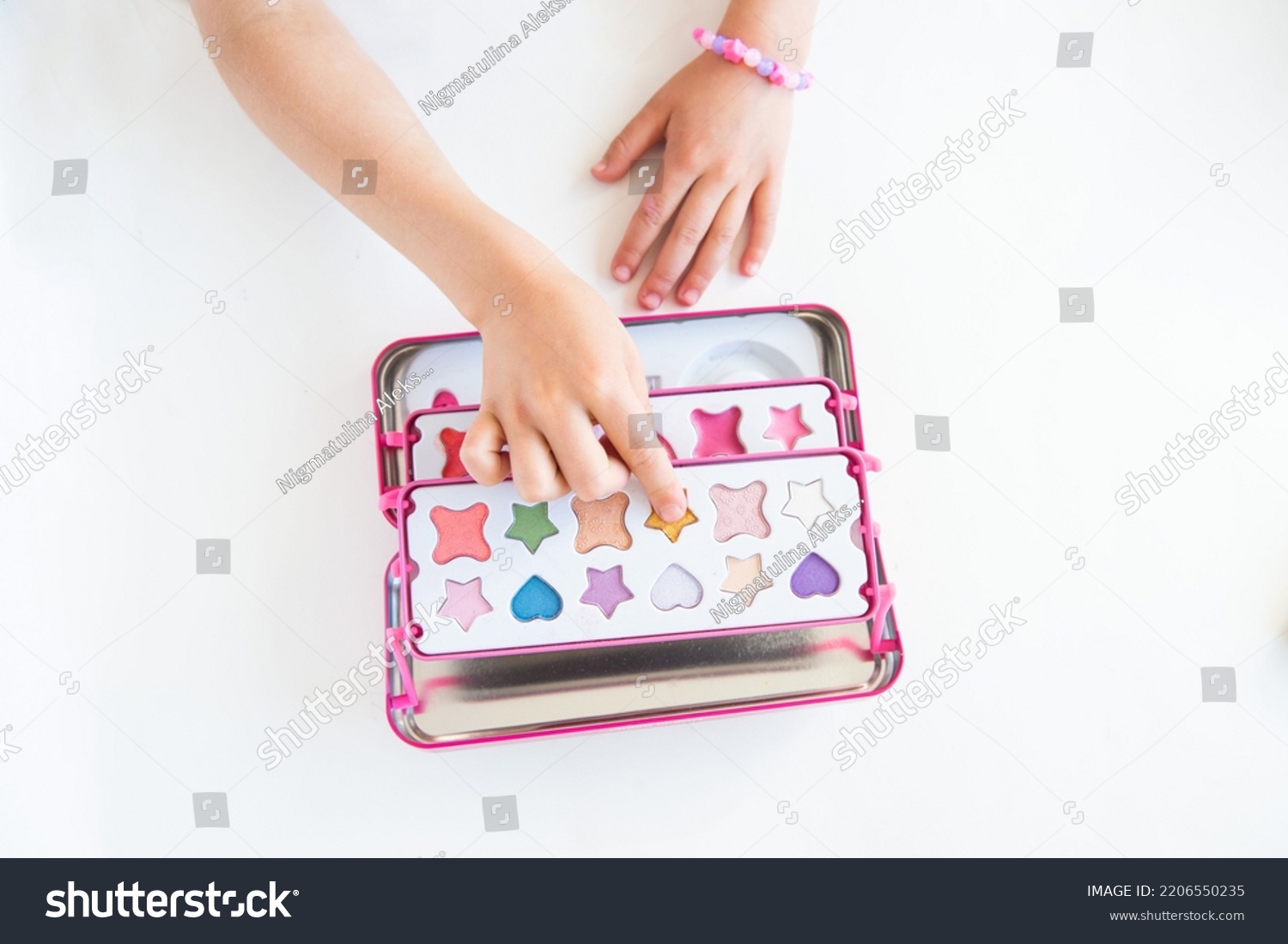 Make up for girls. A little girl plays with a children's set of decorative cosmetics. #2206550235
