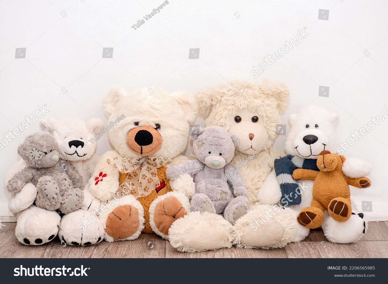 Many soft different bears are sitting on the background of a white wall #2206565985
