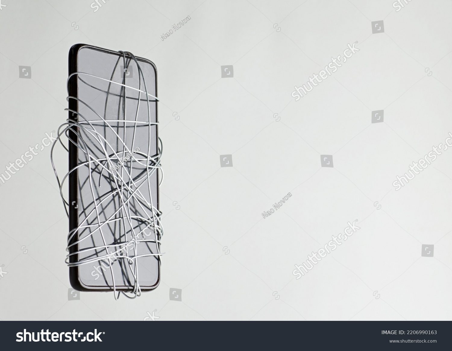 smartphone coiled metal wire in the hands of a man, gray-green background, censorship of social networks. cancel cultural ban, erase #2206990163
